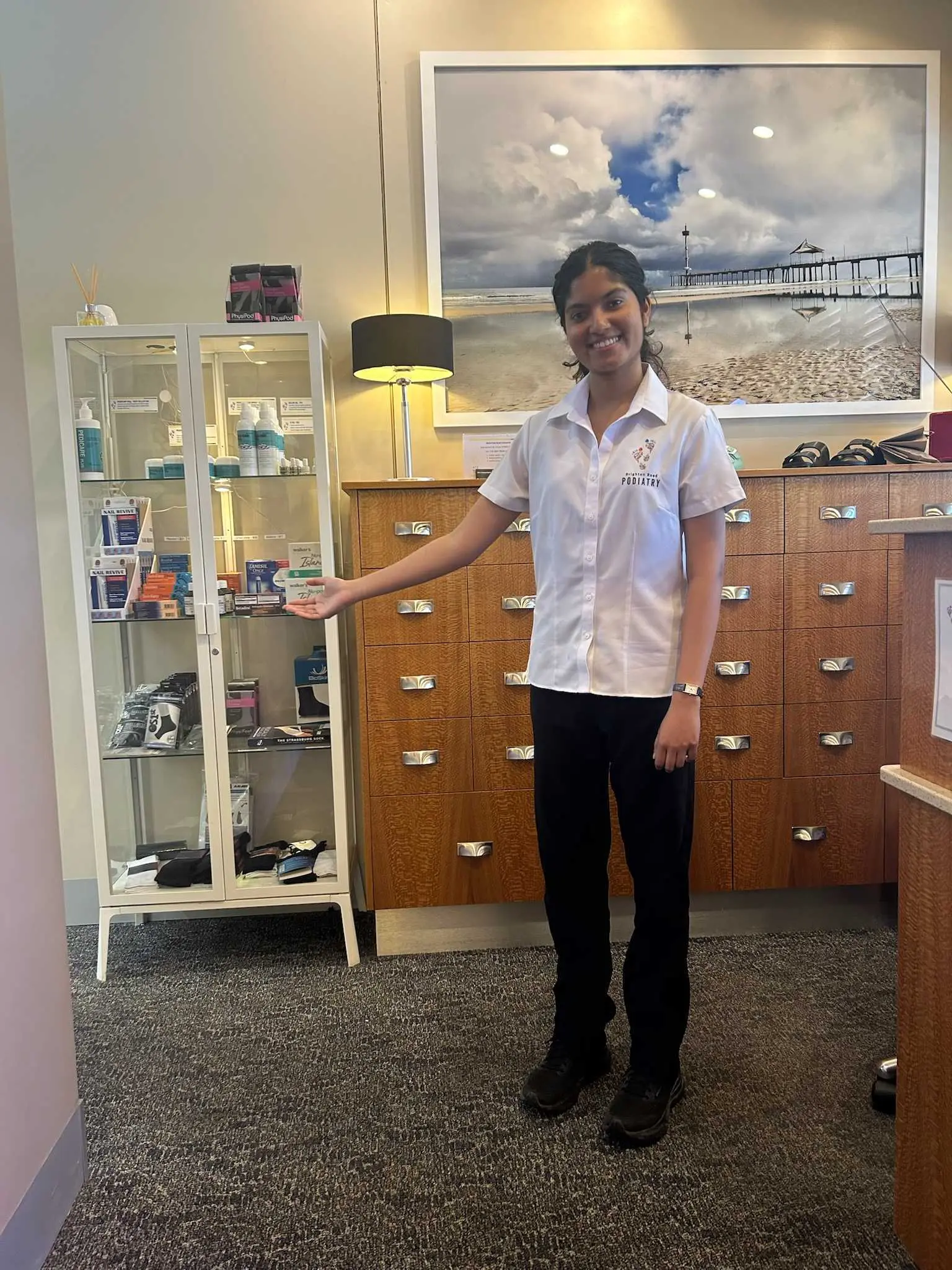 Sonia Gopinath, podiatrist at Brighton Road Podiatry, showcasing foot care products to support foot health and mobility.